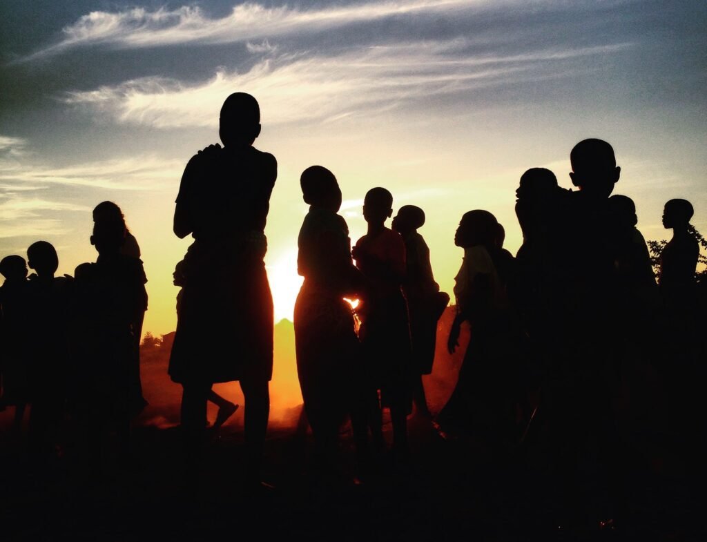Silhouettes of a group of people against a vibrant sunset sky in Lilongwe, Malawi.