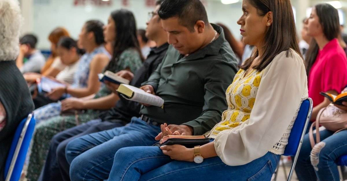 Men and women attending a Christian meeting in Ciudad de México, reading books indoors.