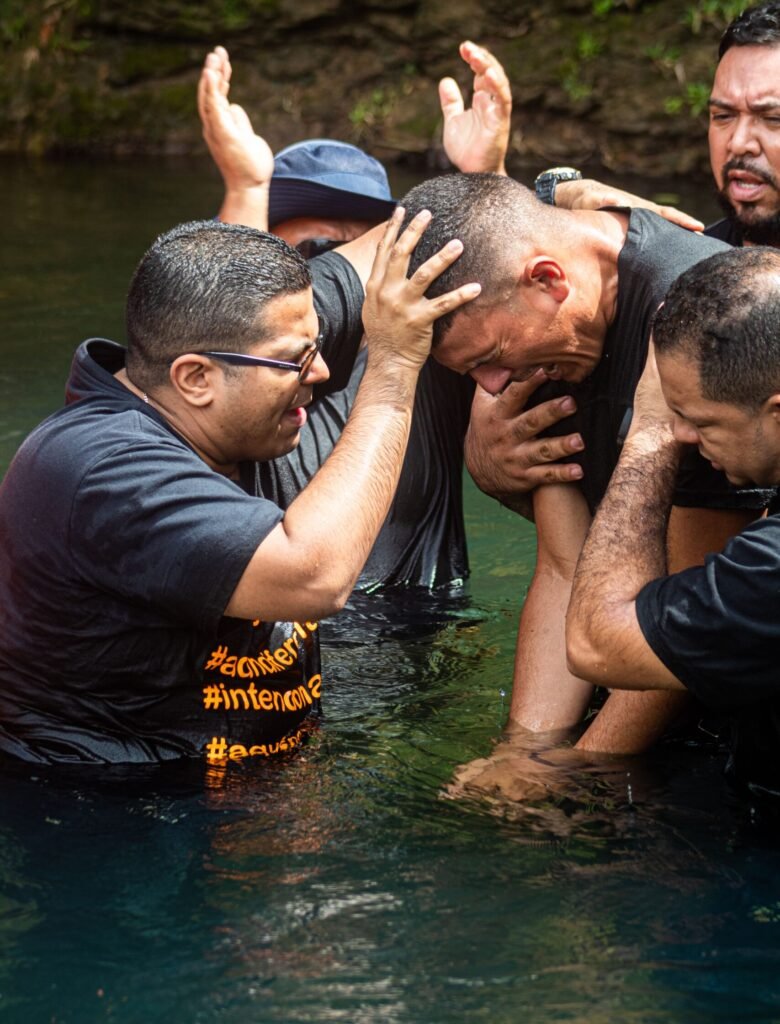 A spiritual baptism ceremony with emotional participants standing waist deep in water.